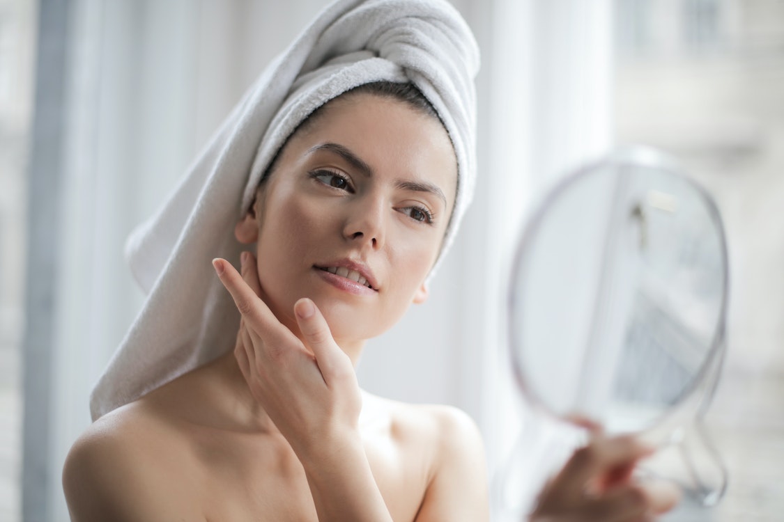 Woman checking her face in the mirror - Advantages of Getting a Botox Treatment 