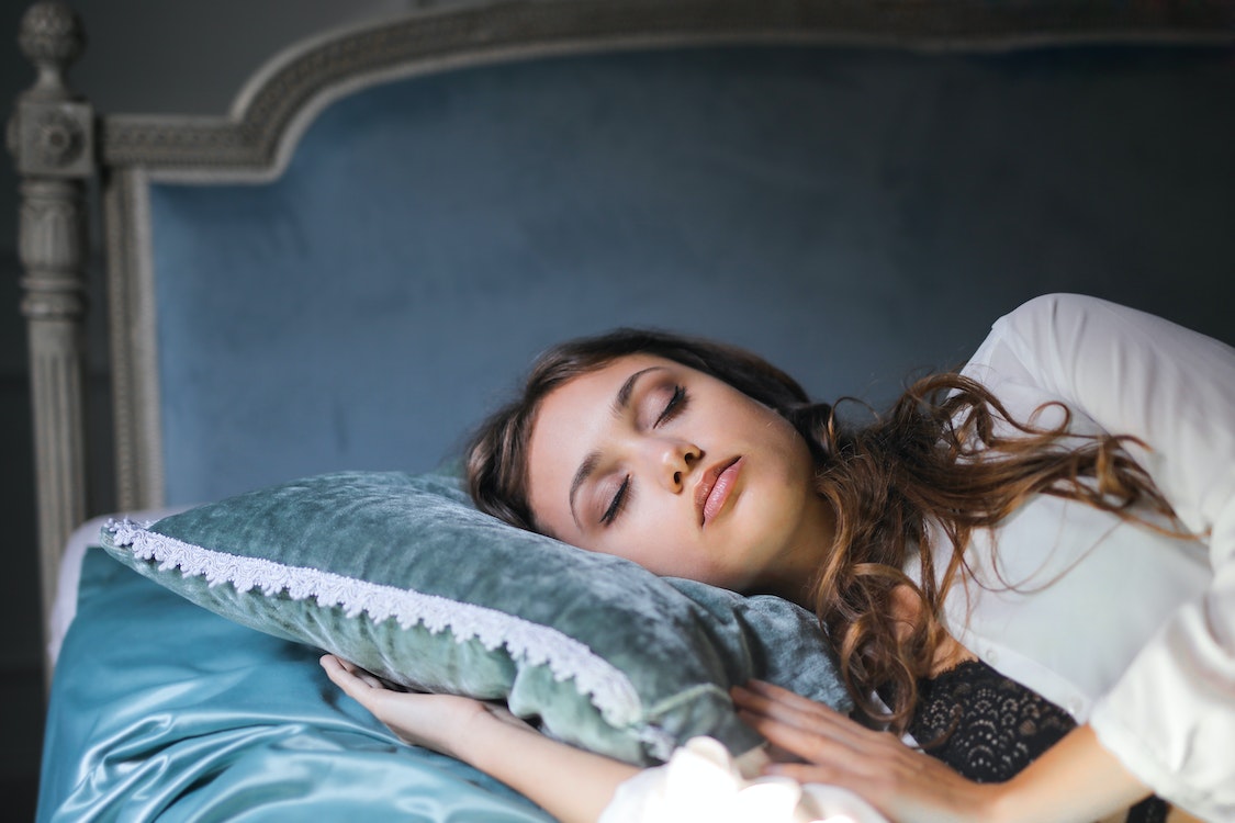girl lying on blue velvet pillow - Best Ways to Improve Your Sleep Quality