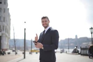 smiling businessman in a suit giving thumbs up and holding a smartphone outdoors in a city setting 300x200 - smiling businessman in a suit giving thumbs up and holding a smartphone outdoors in a city setting..jpg