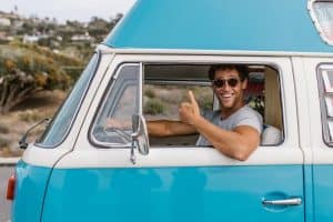 smiling man giving thumbs up while driving a vintage blue camper van outdoors 300x200 - smiling man giving thumbs up while driving a vintage blue camper van outdoors..jpg