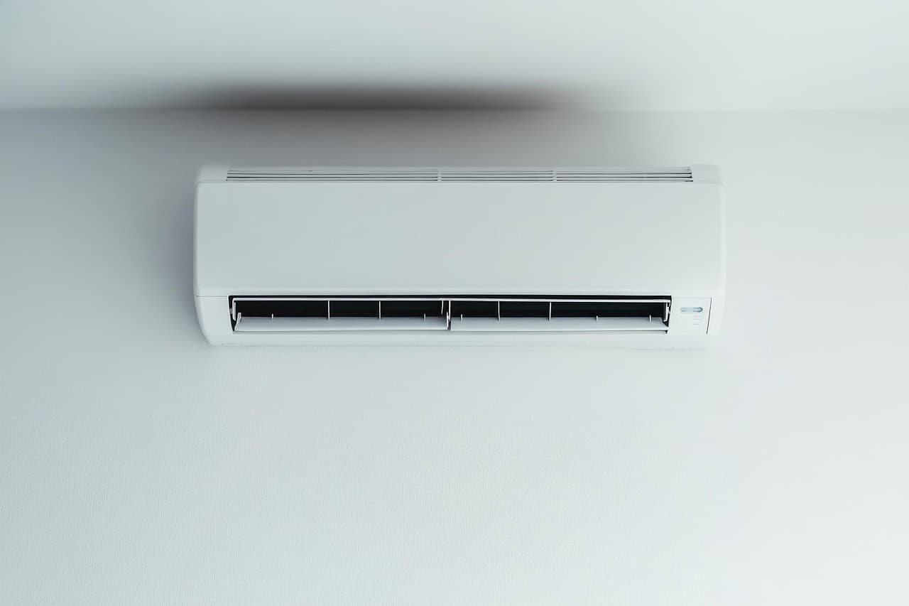 an ac unit attached on a white wall - 5 Air Conditioner Maintenance Tips for Better Efficiency