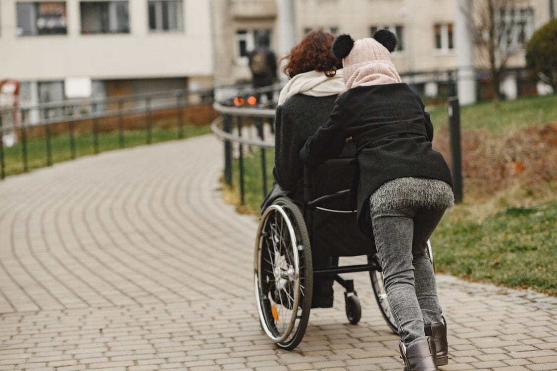 a woman pushing the wheelchair of another woman - How the 2026 Cost of Living Bump Changes the SSDI Math for Arizona Workers